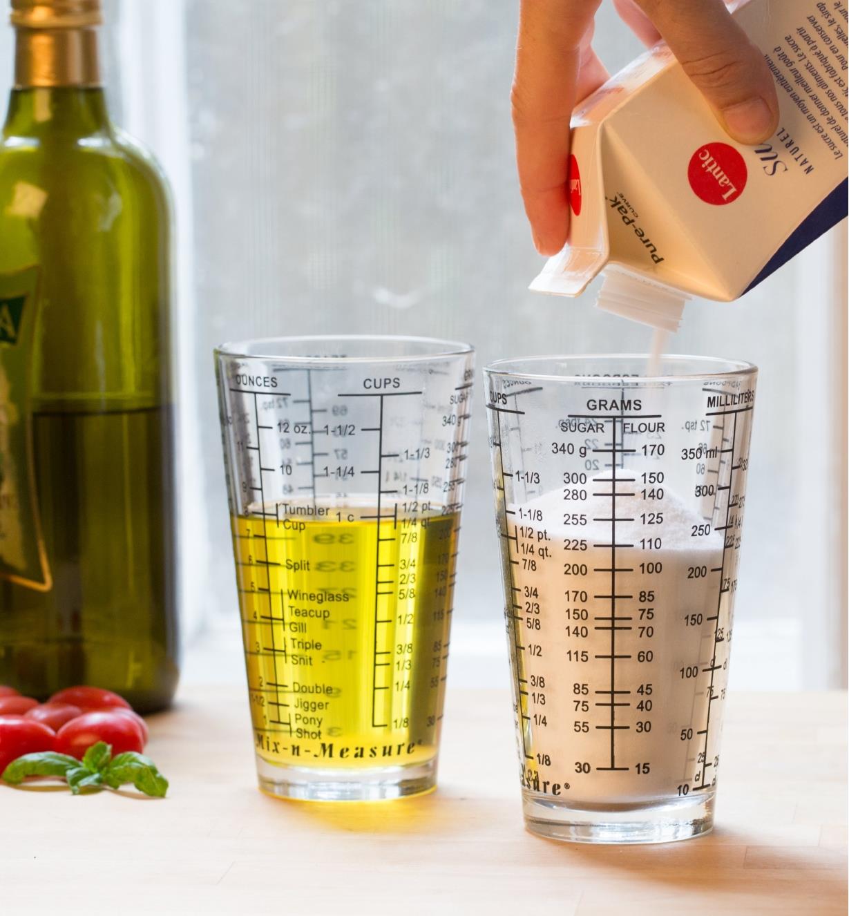 Two measuring glasses, one holding sugar and the other oil