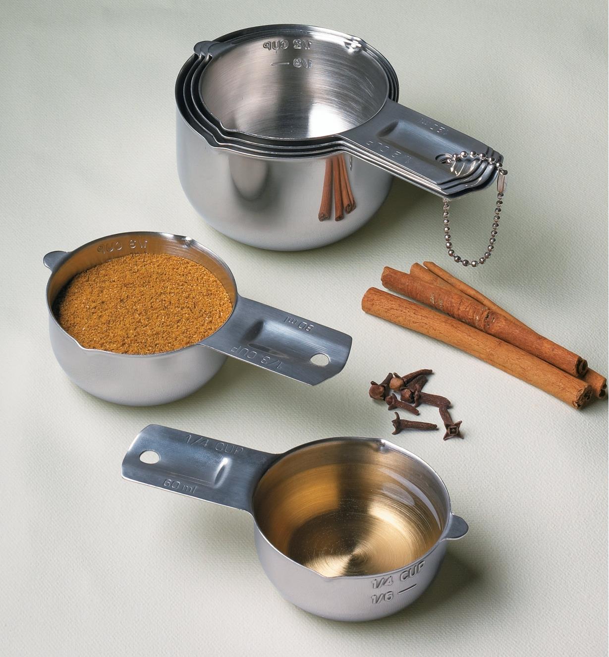 Set of 6 Lifetime Measuring Cups, one filled with ground cinnamon and another with oil