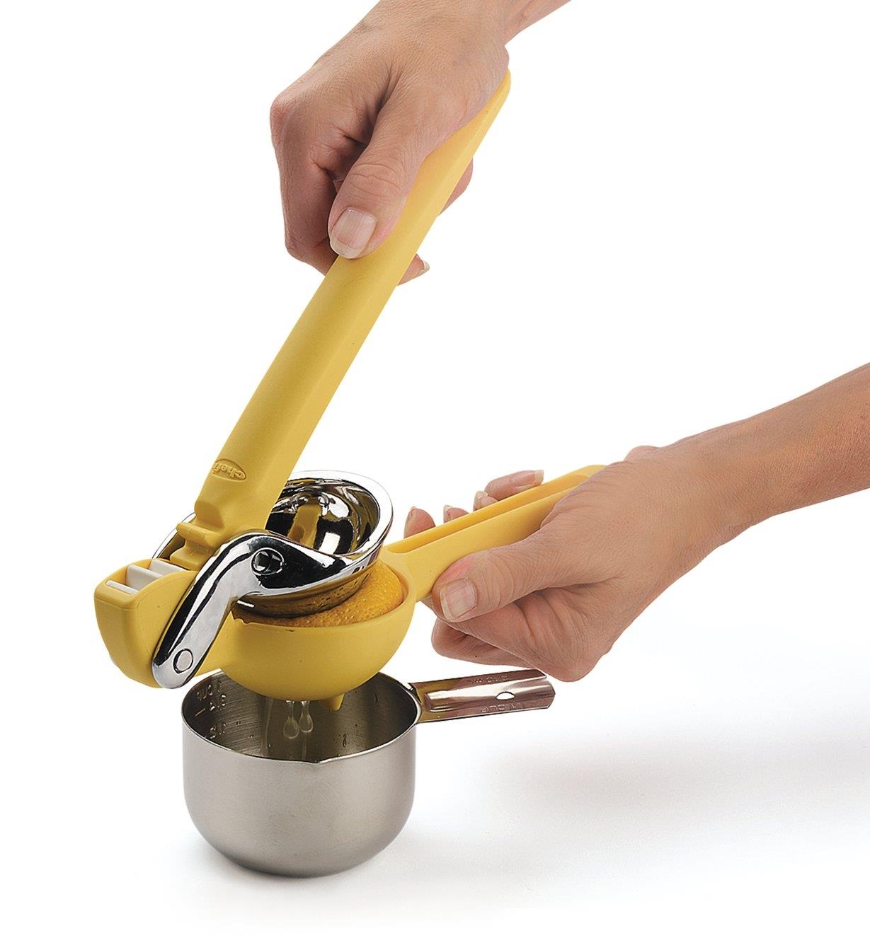 Personne extrayant le jus d'un citron dans une tasse à mesurer avec un presse-citron