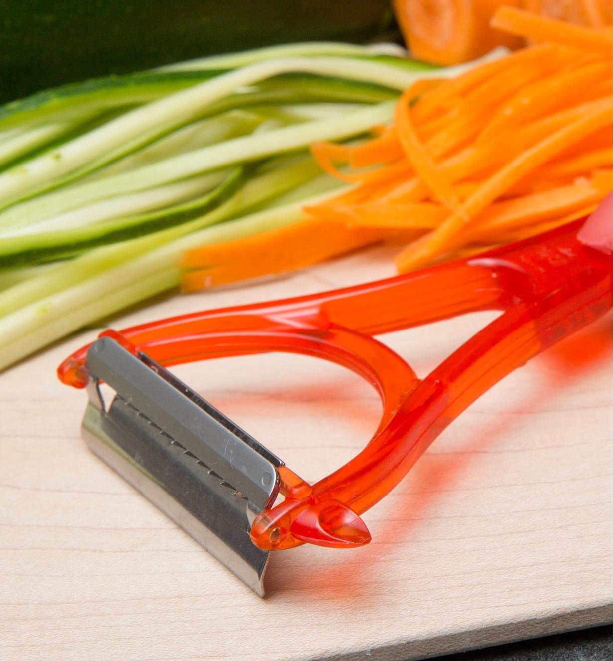 Julienne Peeler on a counter next to julienned carrots and beans
