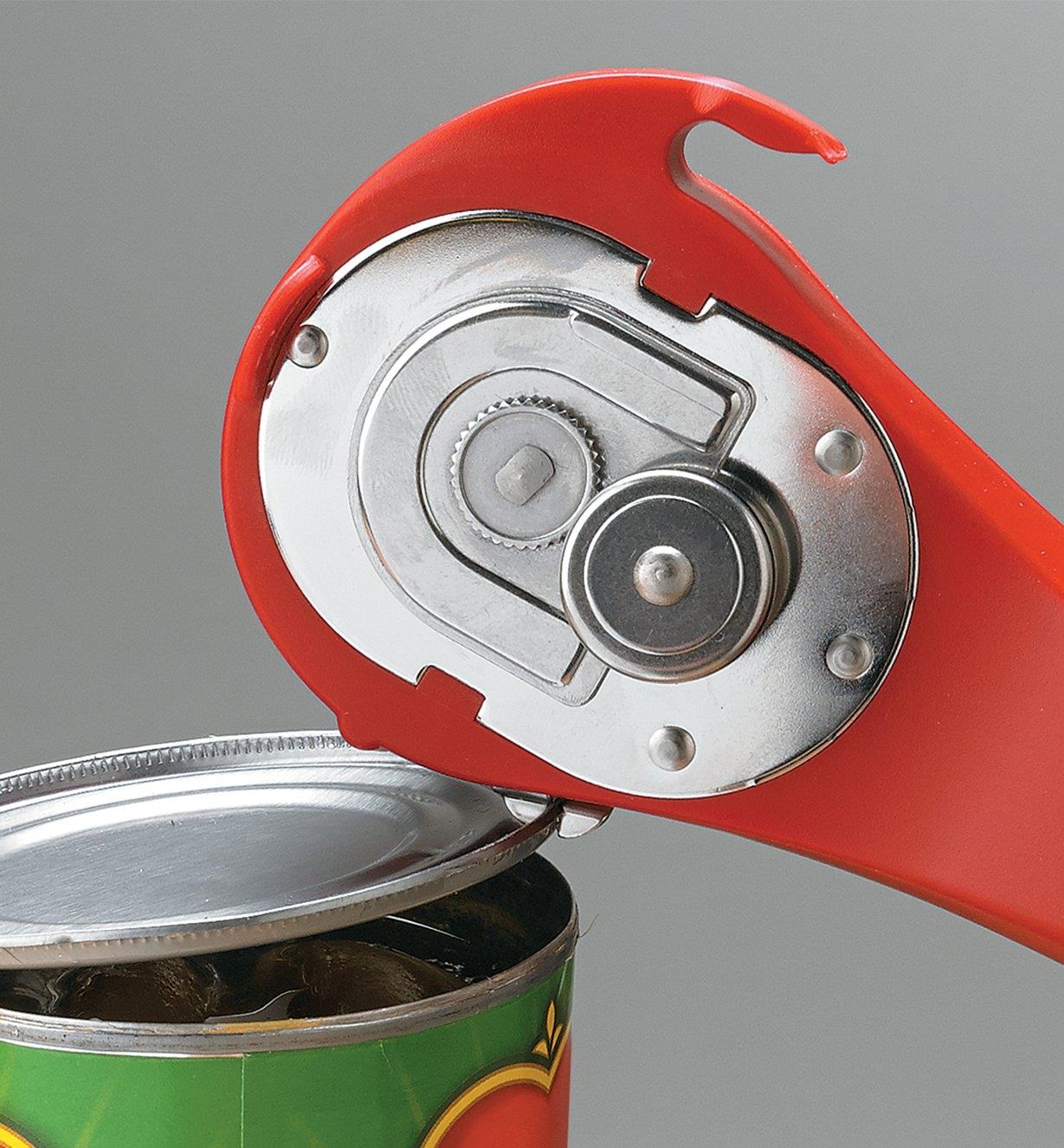 Using the pincers on the side of the can opener to lift the lid off a can