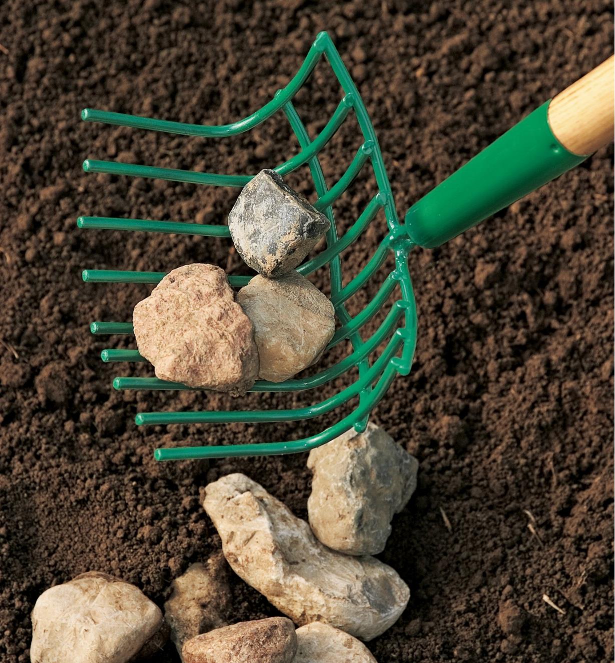 Scooping rocks from soil into the rock rake's basket-like head