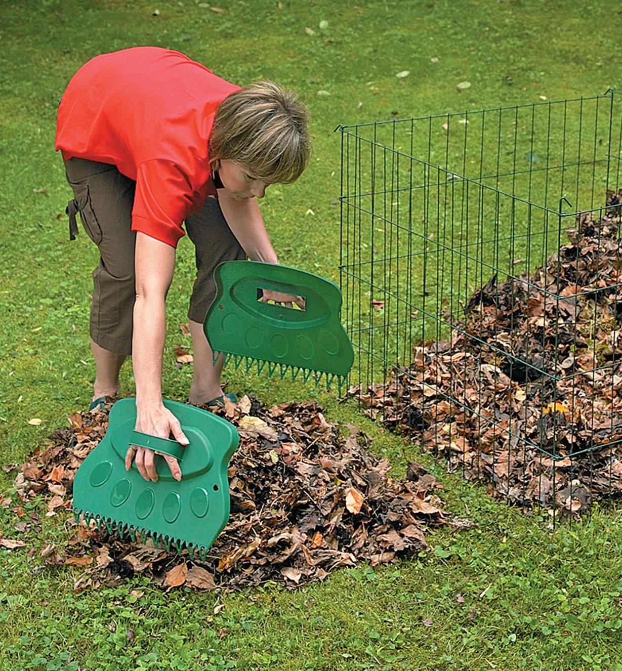 A woman uses Leaf Paws to pick up a pile of leaves on a lawn