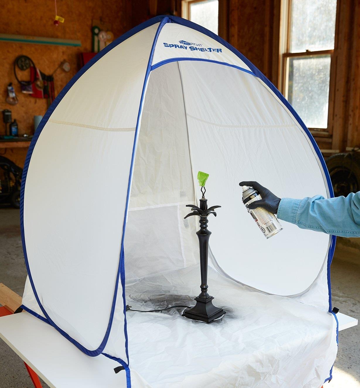 Spray painting a lamp stand inside a Small Portable Spray Shelter