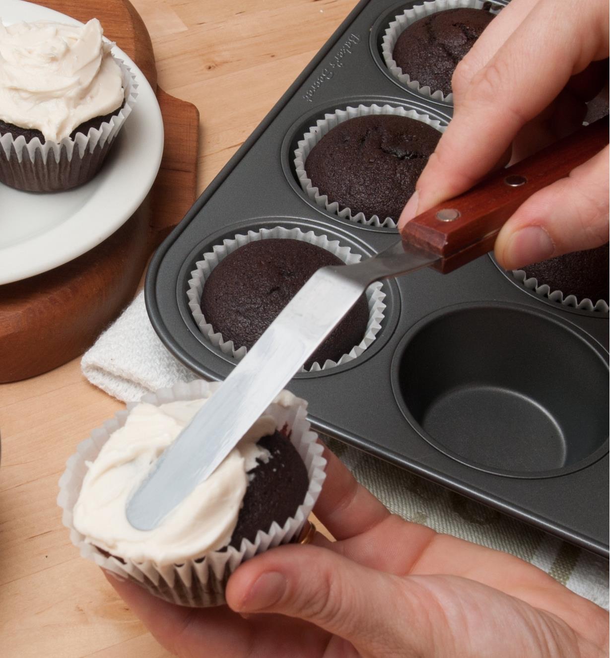 Using the blade tip of the spatula to spread frosting on a cupcake