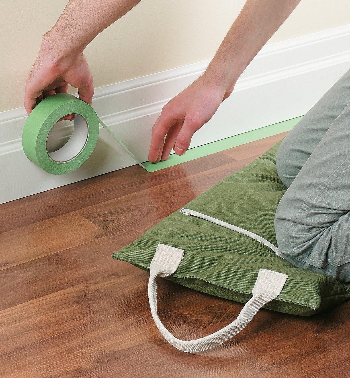 Kneeling on the Portable Canvas Utility Cushion while applying painter's tape to a floor