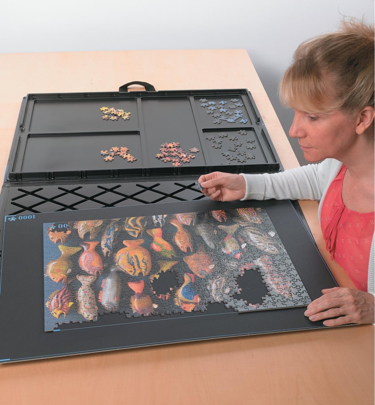 A woman assembles a puzzle on the assembly board of the puzzle caddy
