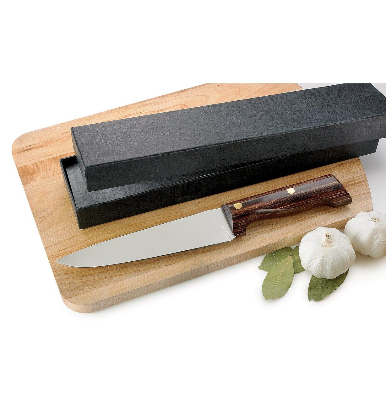 Peasant Chef's Knife on a cutting board next to the presentation box that comes with it 