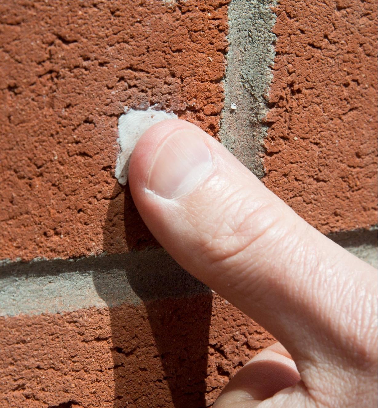 Pressing Epoxy Putty into a hole in a brick wall