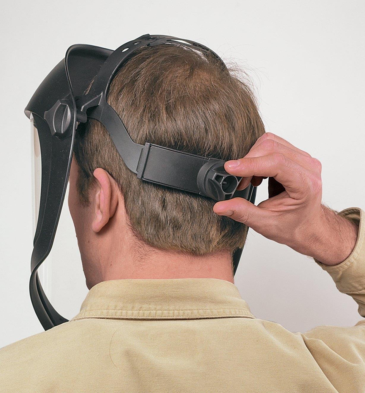 Back view of a man wearing the Professional Face Shield, adjusting it using the rear knob