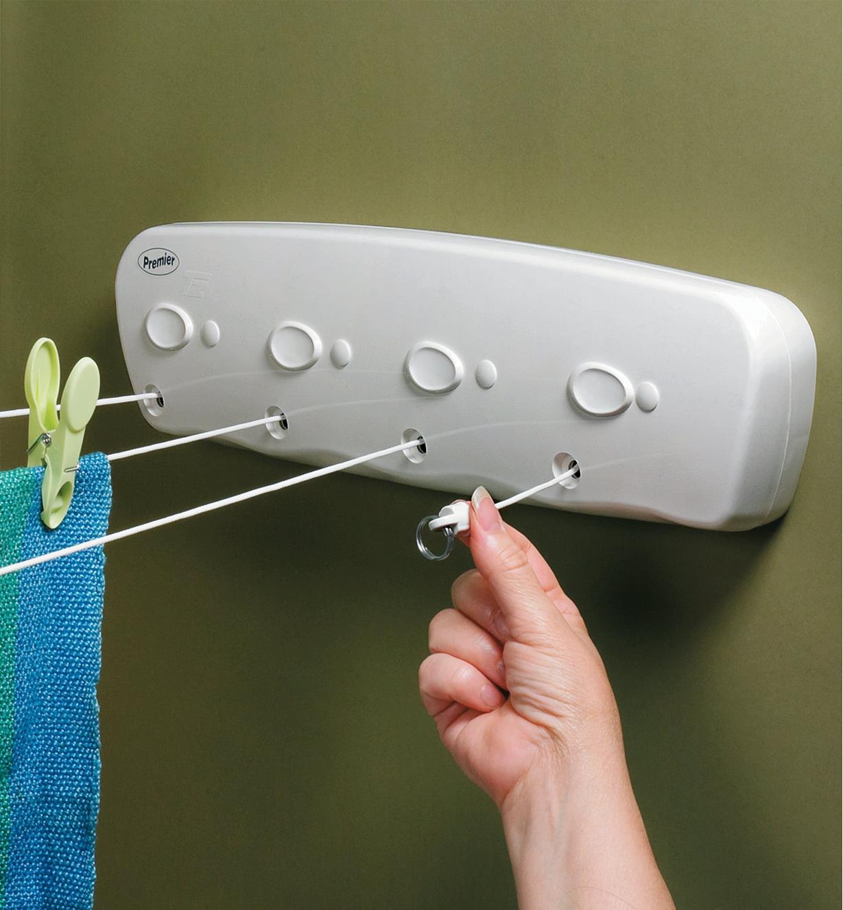 Withdrawing one of the lines on a four-line retractable clothesline that is mounted on a wall