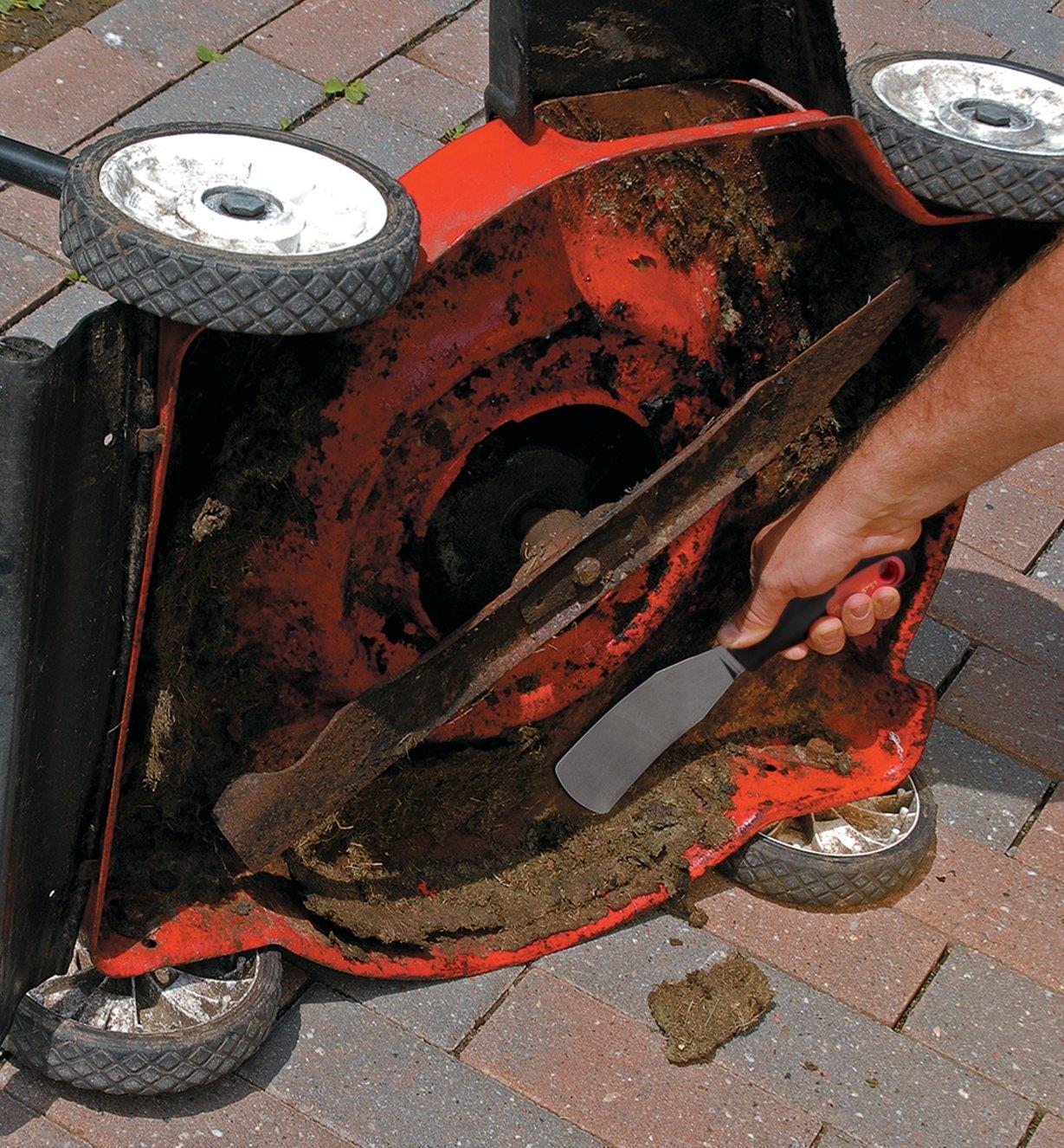Grattoir pour tondeuse Grassbuster employé pour déloger les débris collés au carter d'une tondeuse