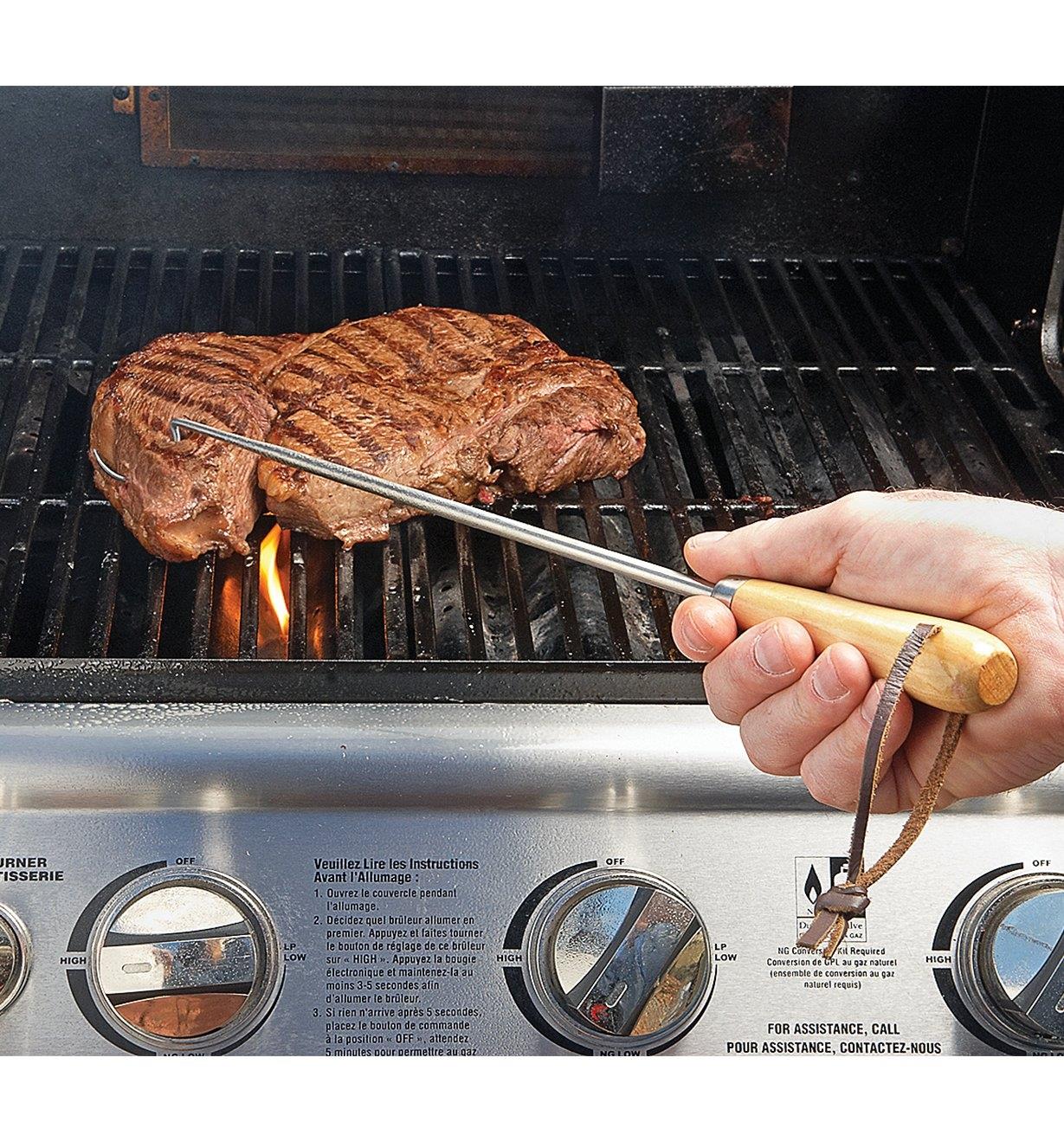 Turning a steak on a barbecue using a Pigtail Flipper