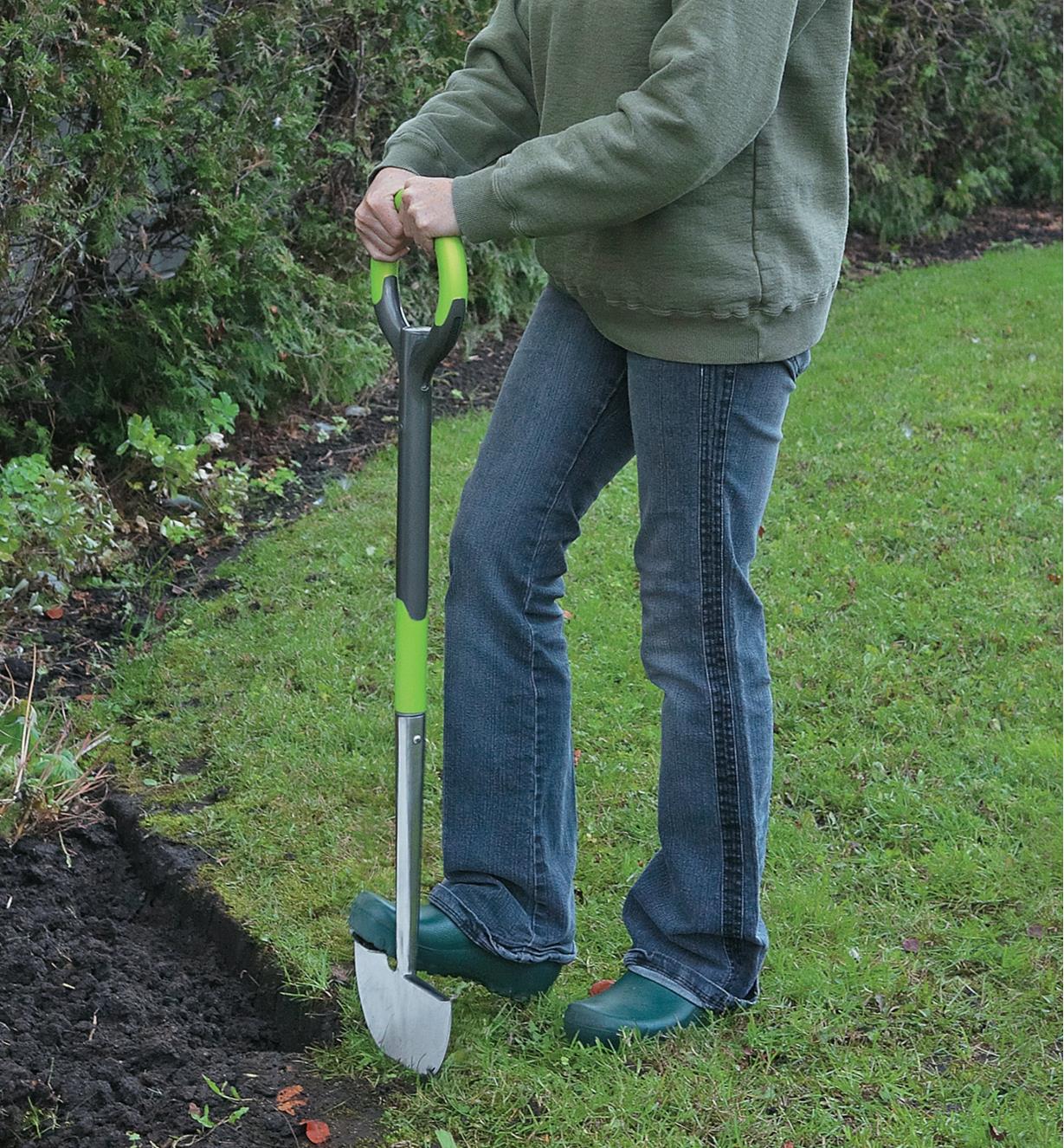 A woman cuts the edge of a garden using the Radius ergonomic edger