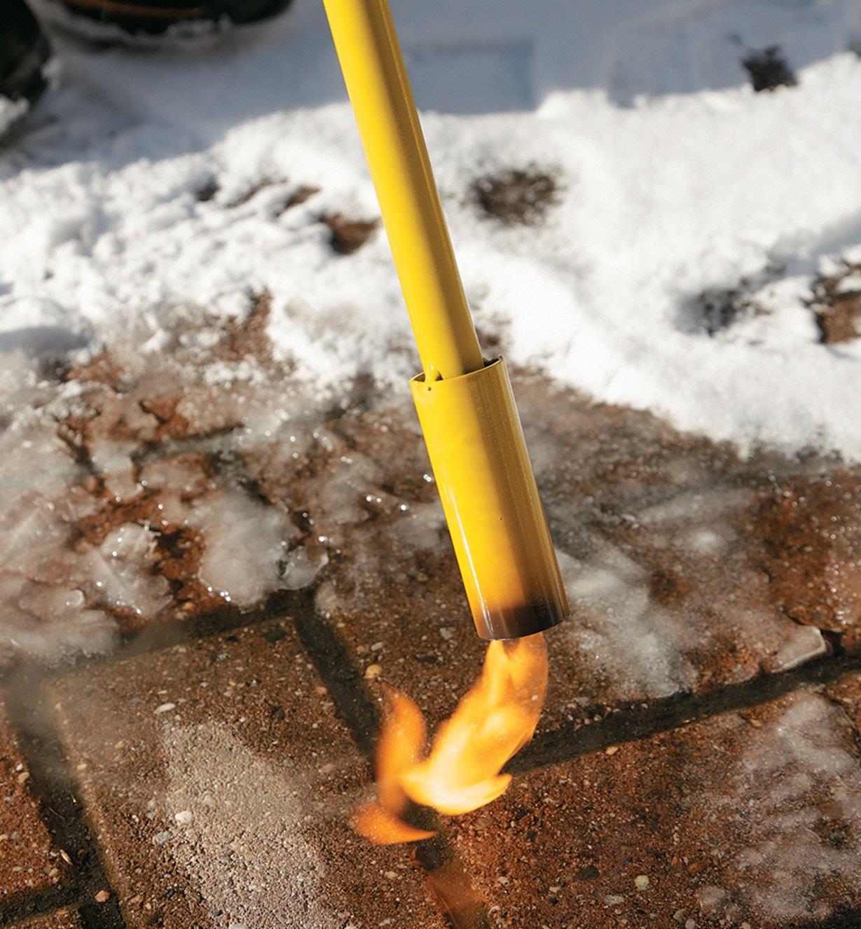 Close-up of flame melting ice on a walkway