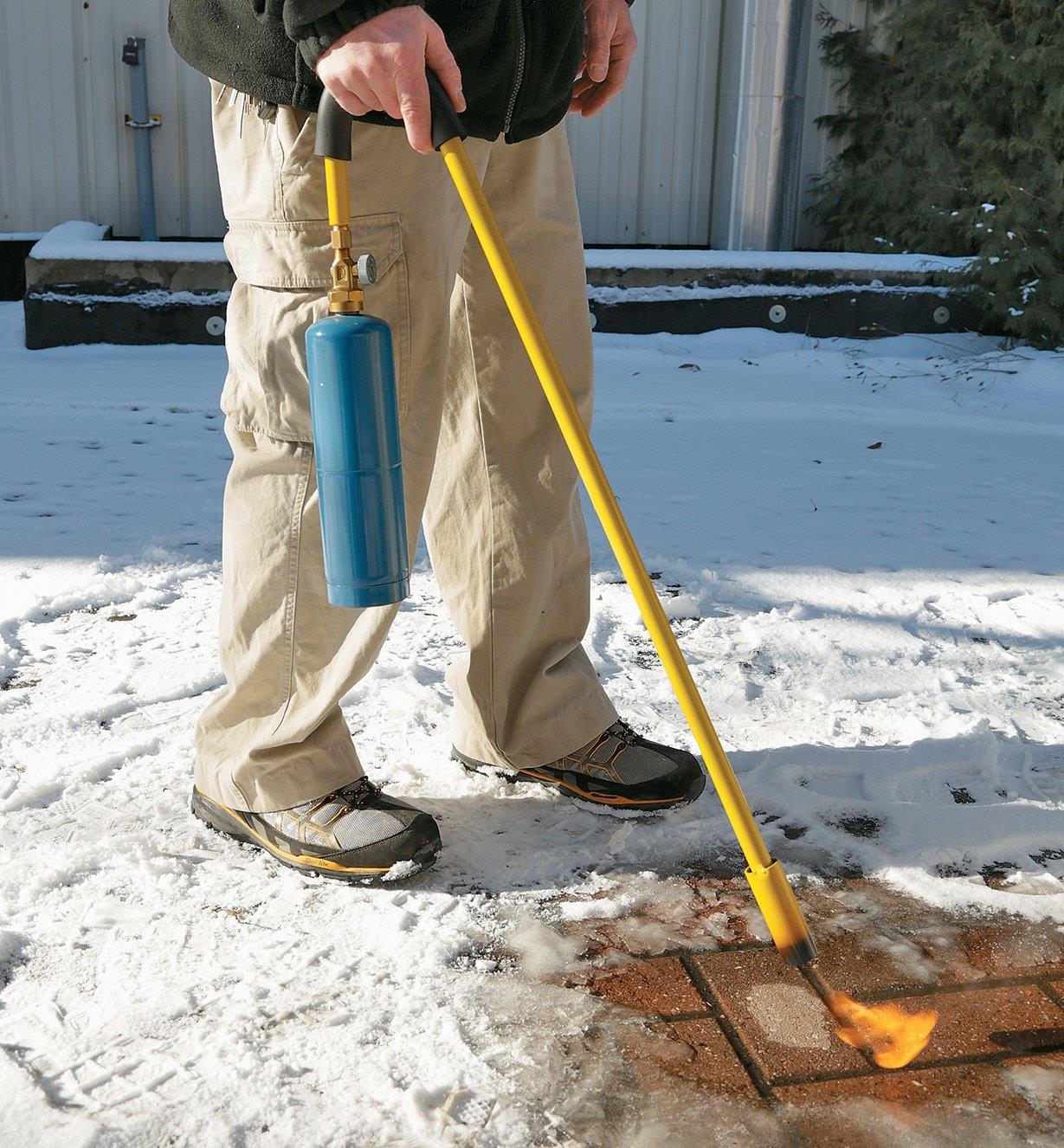 A man melts ice on a walkway using the Mini Weed Torch