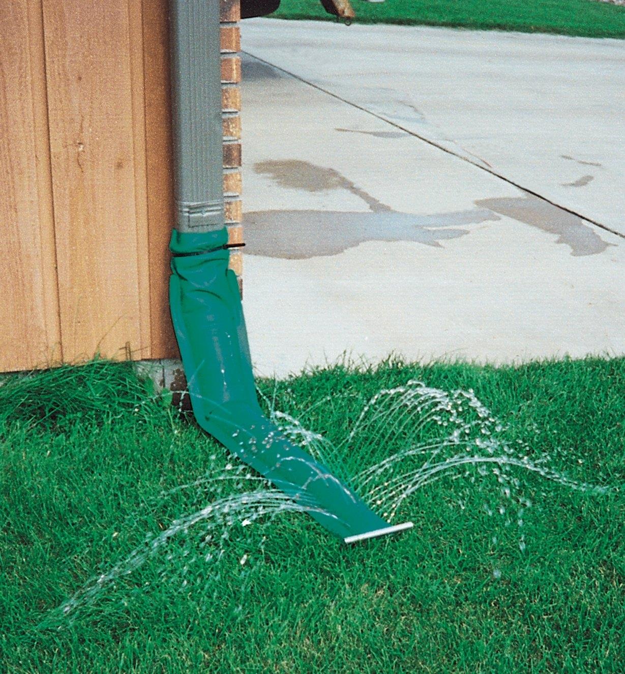 Recoil Downspout Sprinkler unrolled and sprinkling water on grass