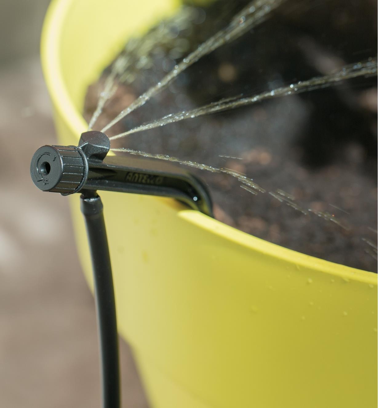 Potstream Emitter attached to the edge of a pot, emitting water