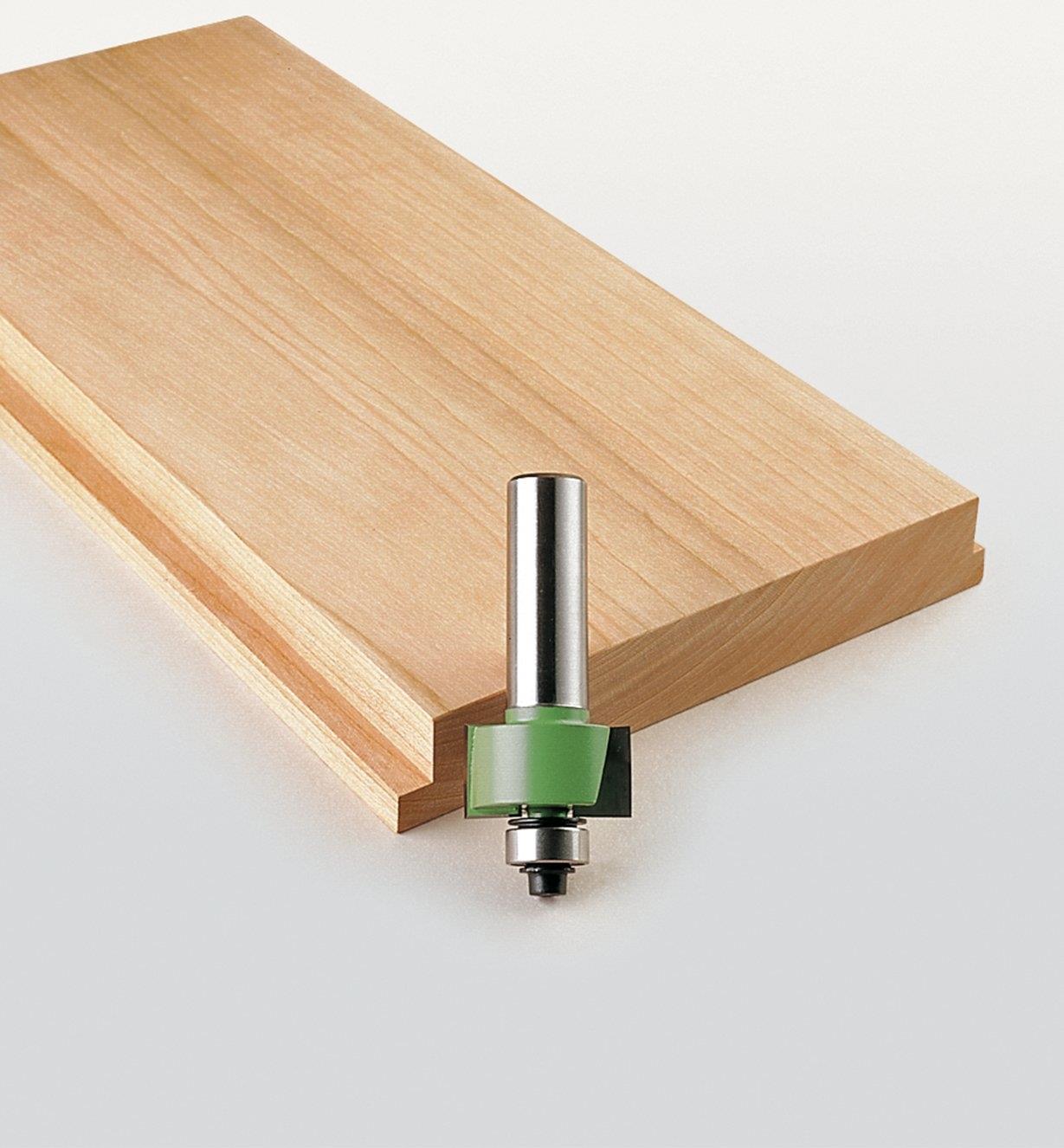 Small rabbeting bit next to a board with a rabbet cut along the edge