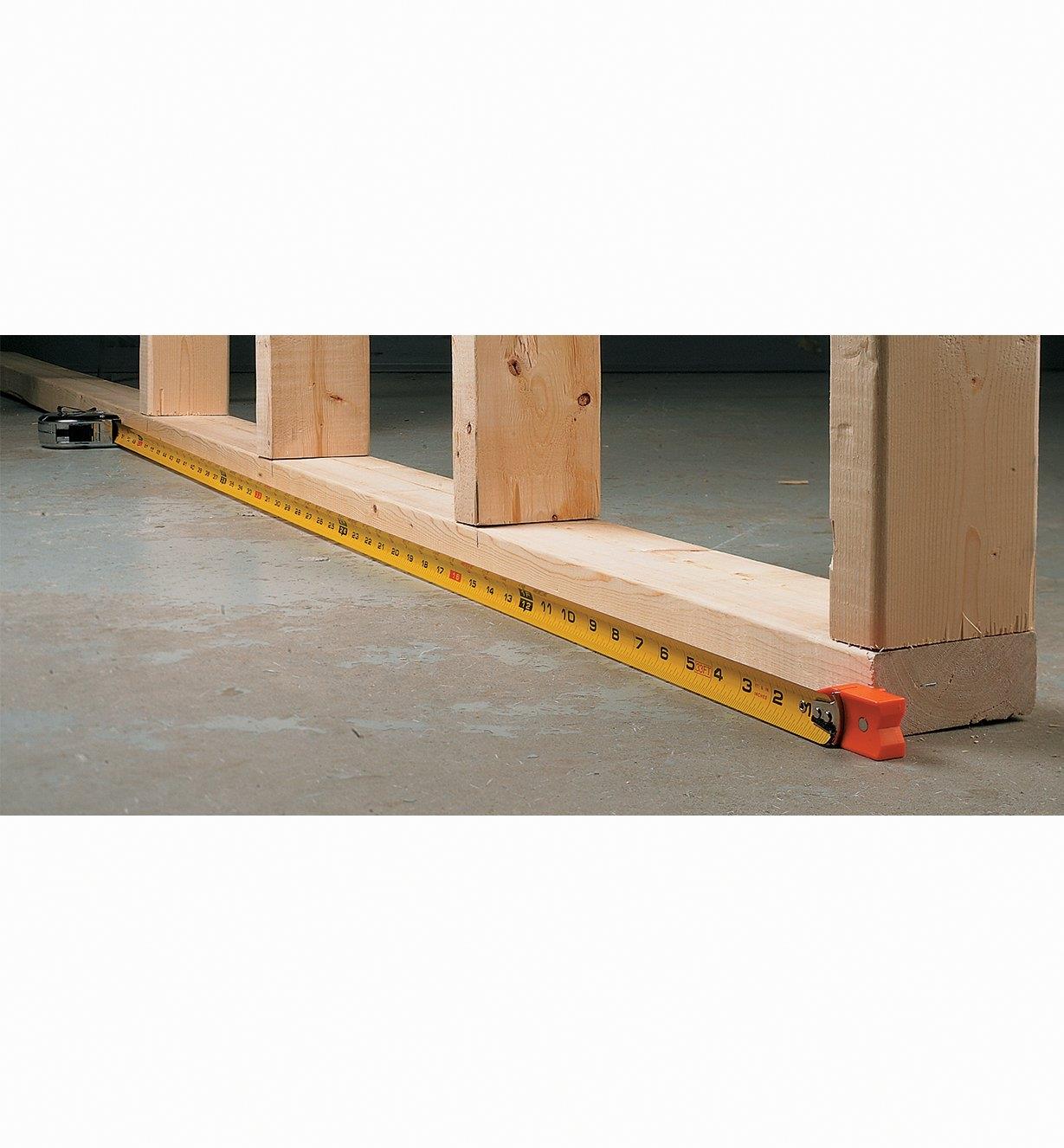 Measuring wooden framing with a tape measure and tape tip