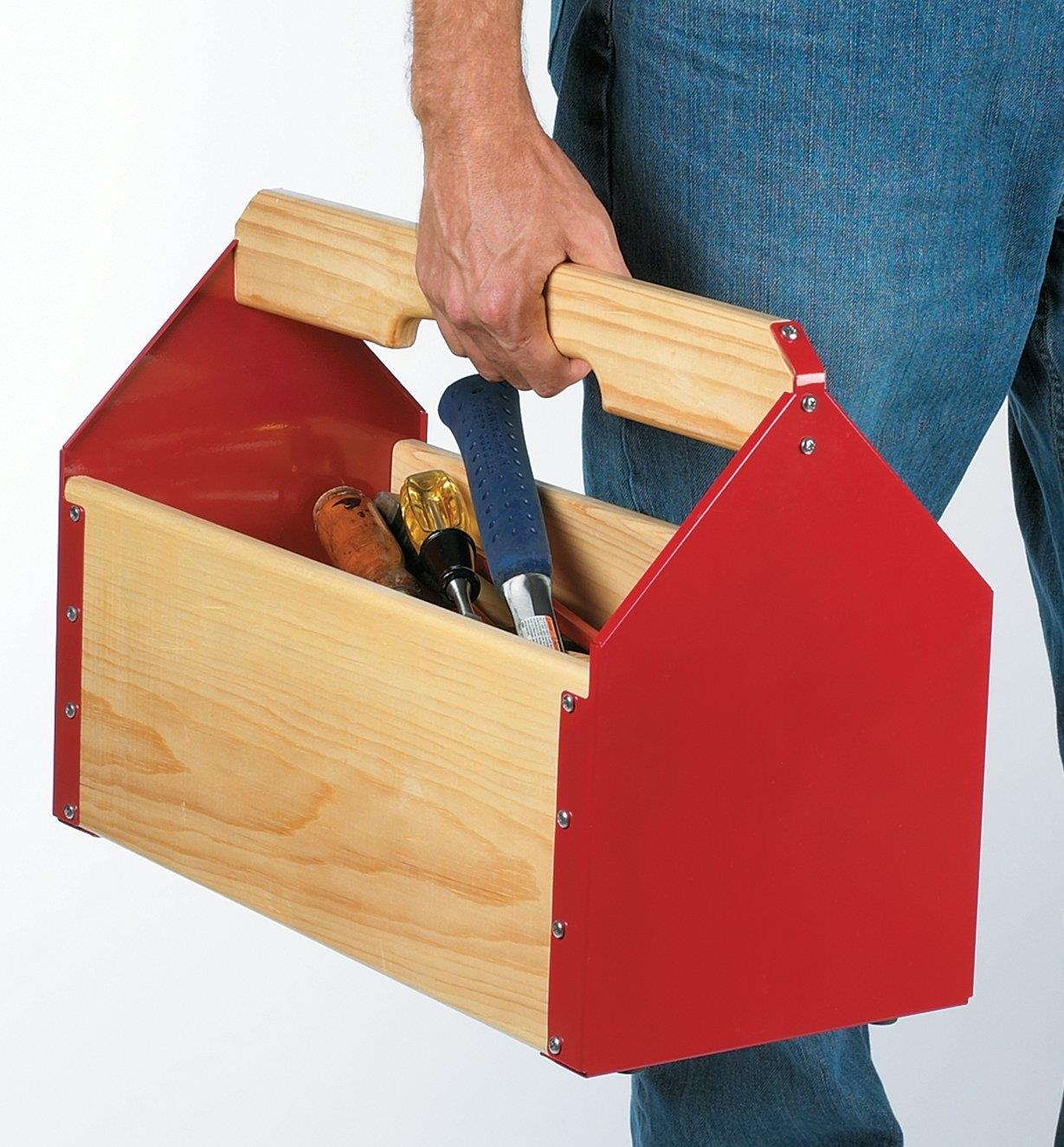 A man carries a toolbox made with toolbox ends filled with tools