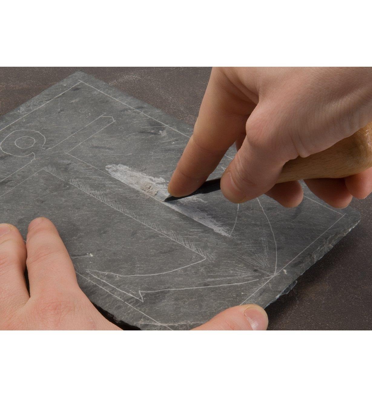 Using a chisel to engrave a design on slate