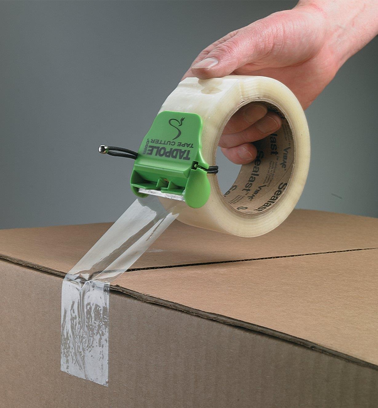 Taping a cardboard box shut using packing tape with the Tadpole Tape Cutter attached