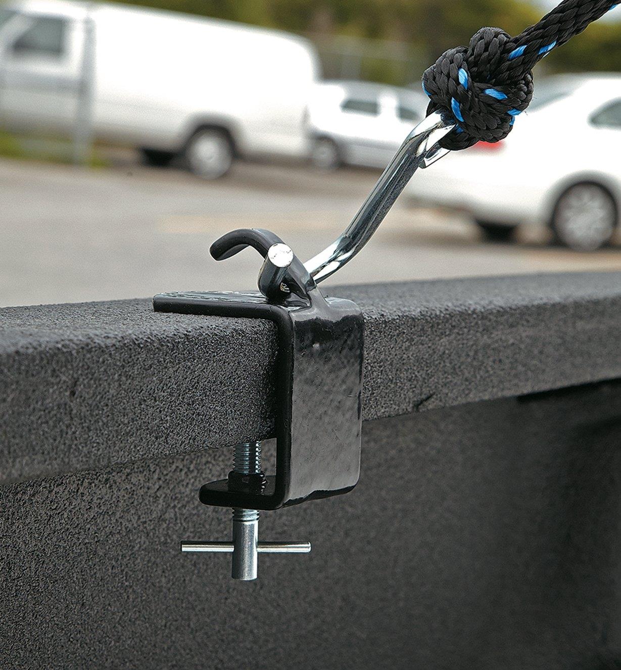 Tie-down anchor clamped to the rail of a pickup truck, with a metal hook attached