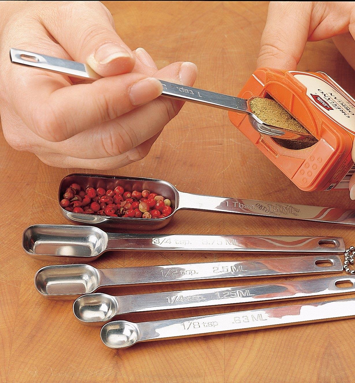Inserting a measuring spoon into the slender opening of a spice container