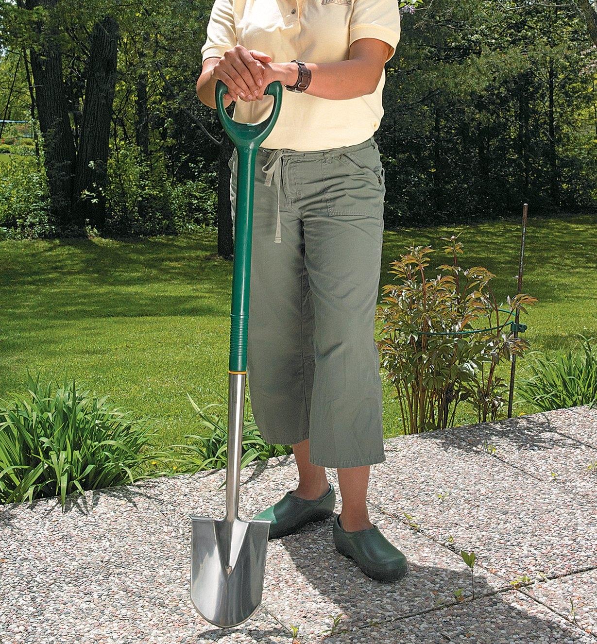 A woman holds the Border Shovel on a patio