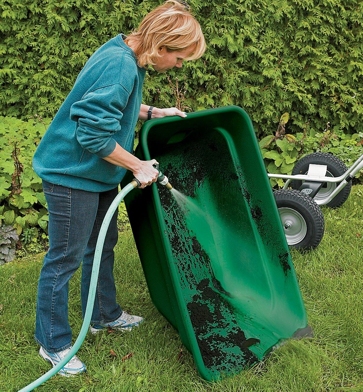 A woman uses a hose to rinse out a Smart Cart