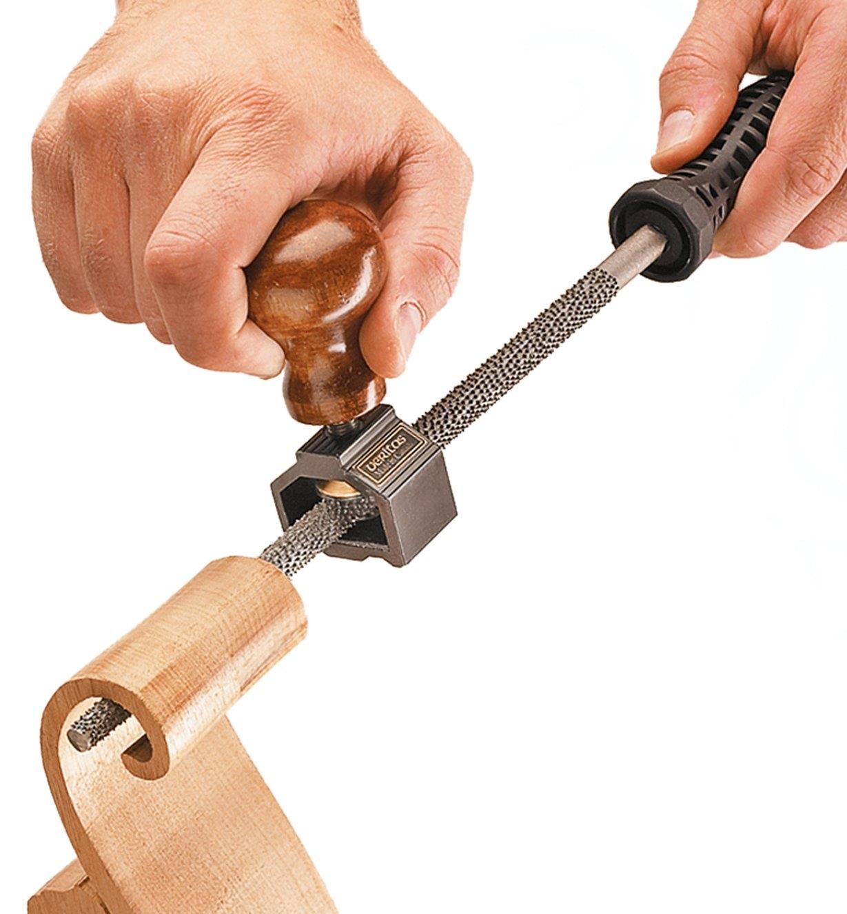 Using a rasp with the file/rasp handle to shape the inside of a wooden scroll
