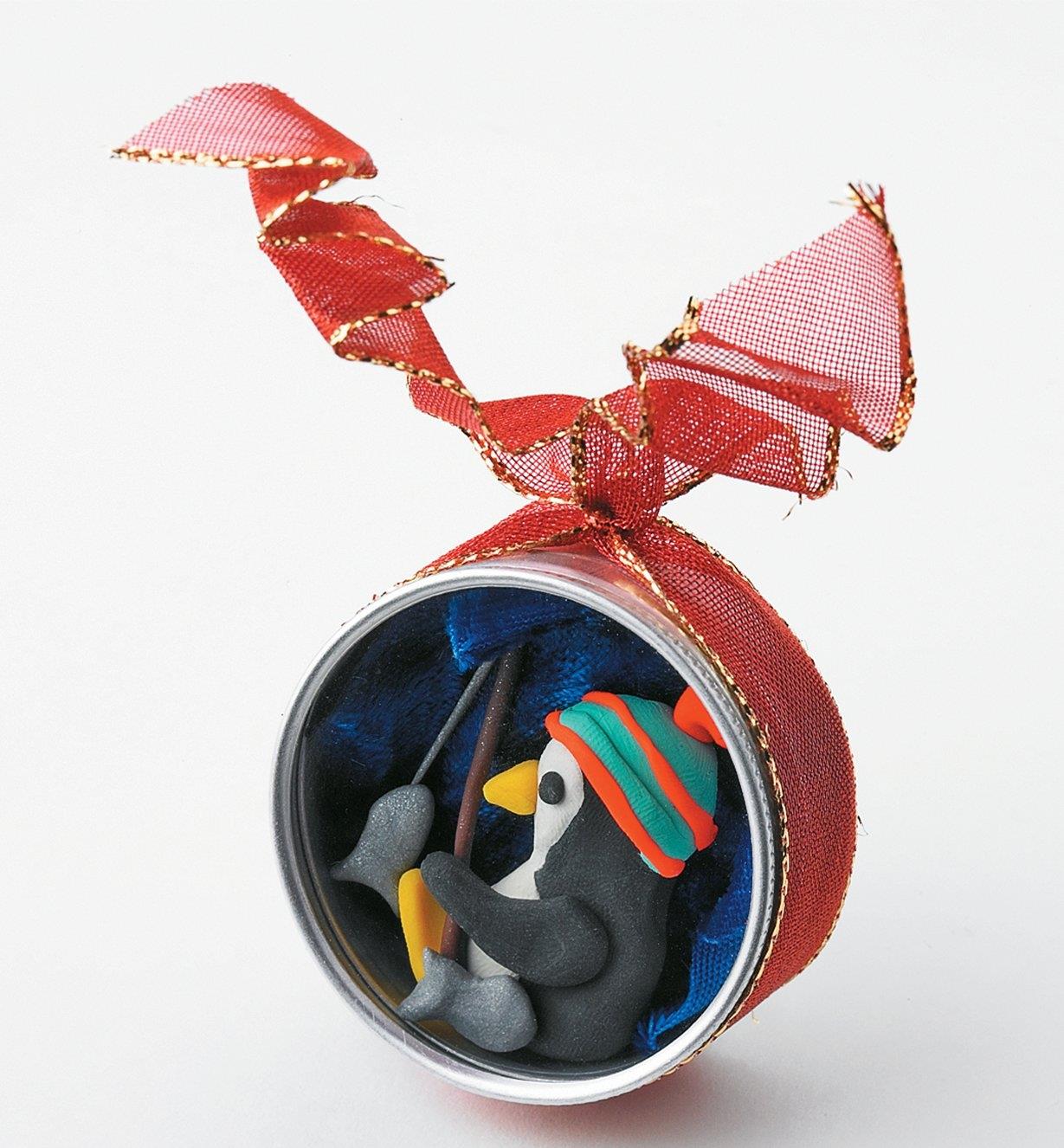 A holiday ornament made with a polymer clay penguin inside a Watchmaker's Case