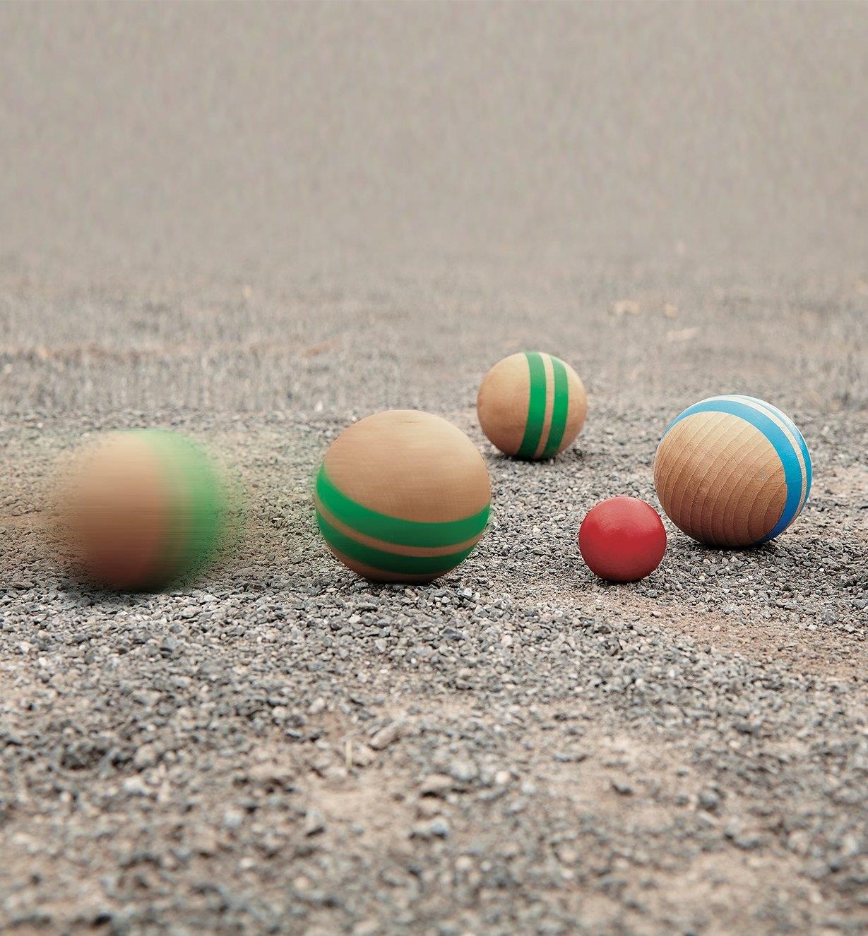 Wooden Pétanque balls rolling on a dirt surface