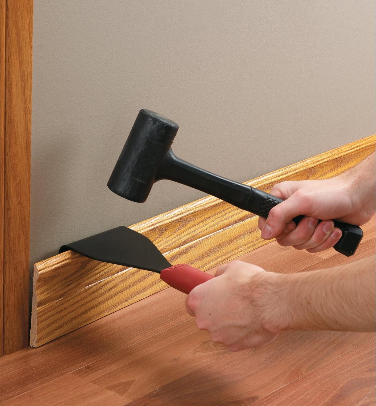 Using the Trim Puller with a mallet to remove a baseboard