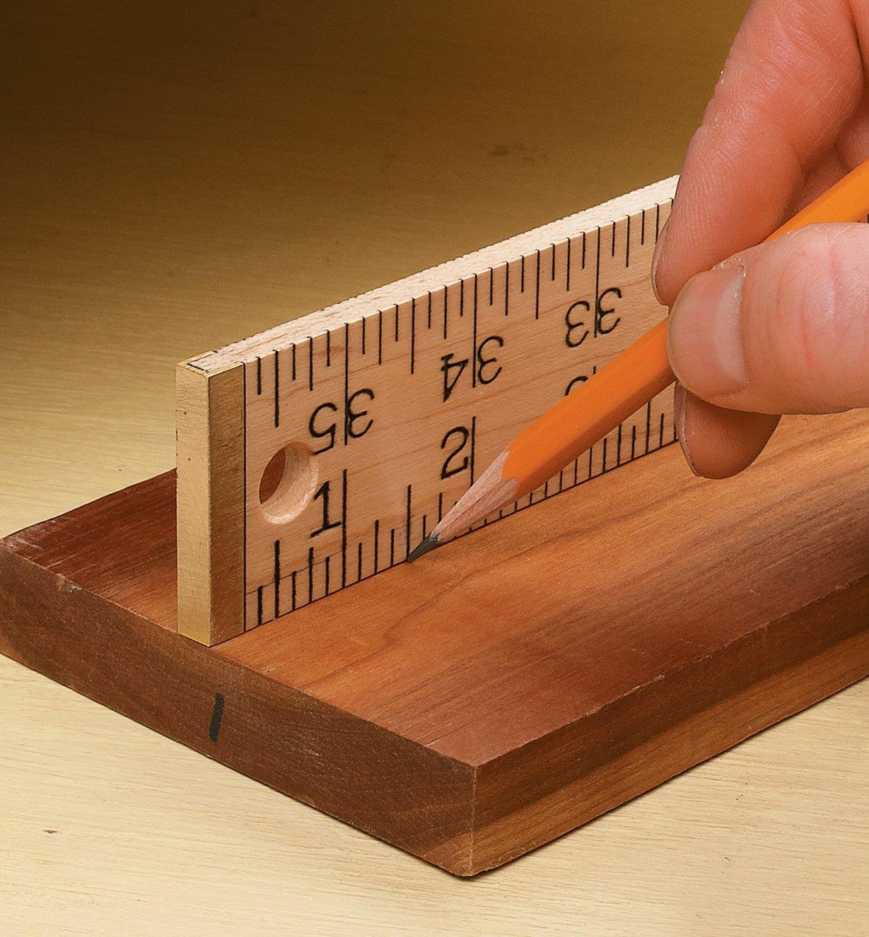 Marking a measurement on a board using a wooden rule standing on edge