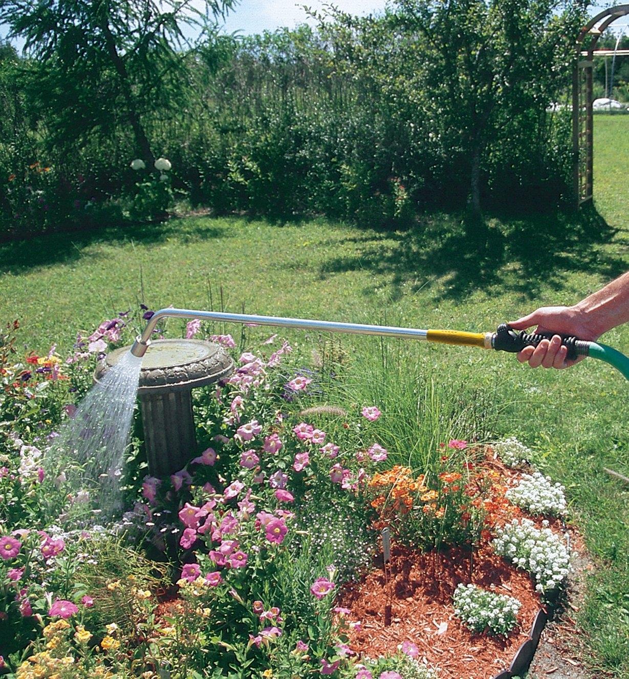 Trigger Valve attached to a water wand, spraying flowers in a garden
