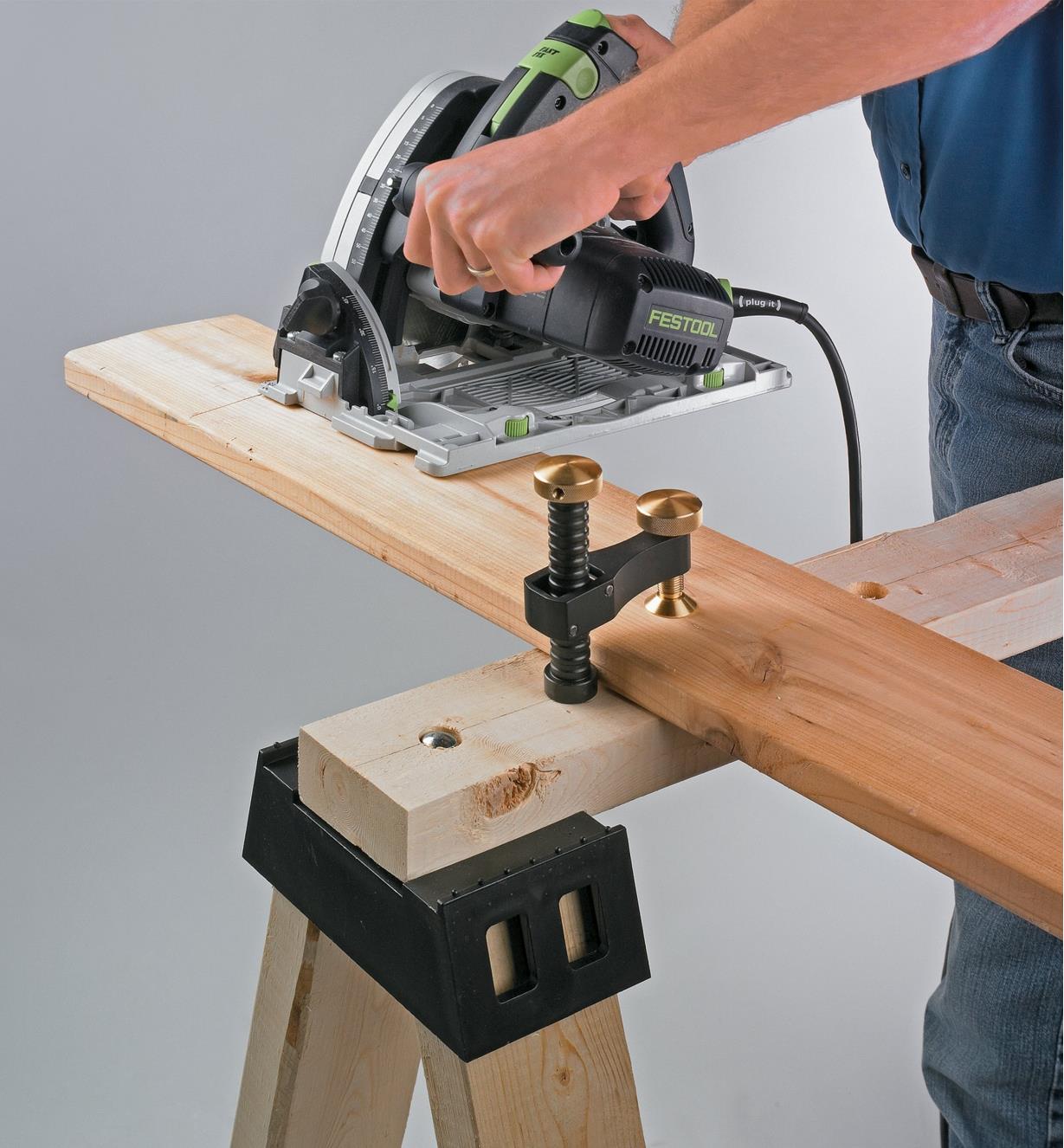 Using the surface clamp to hold a board on a sawhorse while cutting with a circular saw