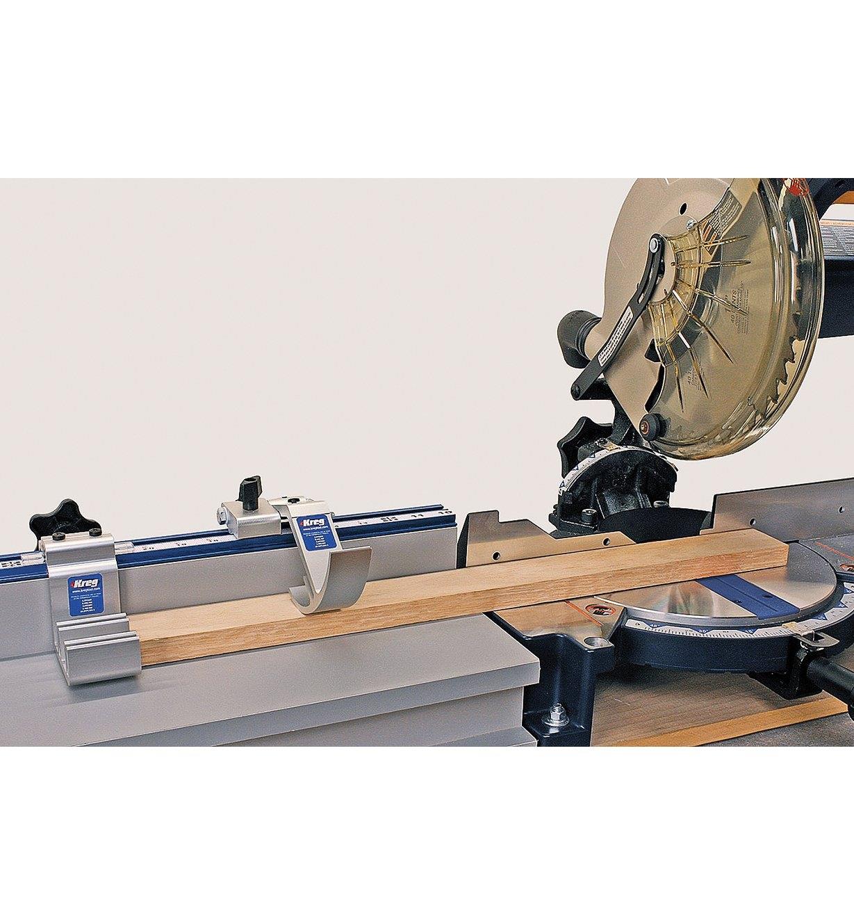 The Kreg Trak and Stop System being used with a miter saw to cut a piece of wood to exact length