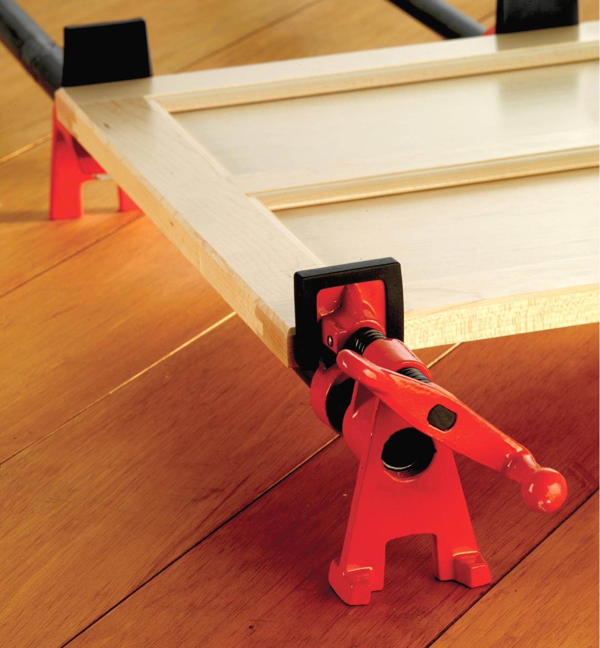 A cabinet door assembly held in a Bessey pipe clamp with Bessey pipe clamp pads mounted on the jaws