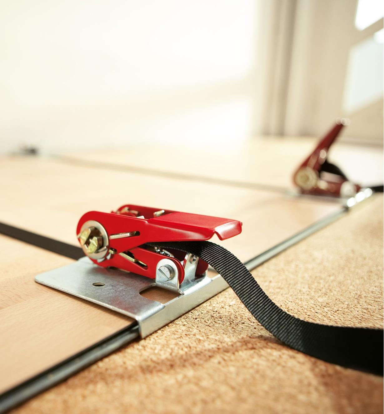 A Bessey flooring clamp strap being used to hold rows of flooring in position during installation