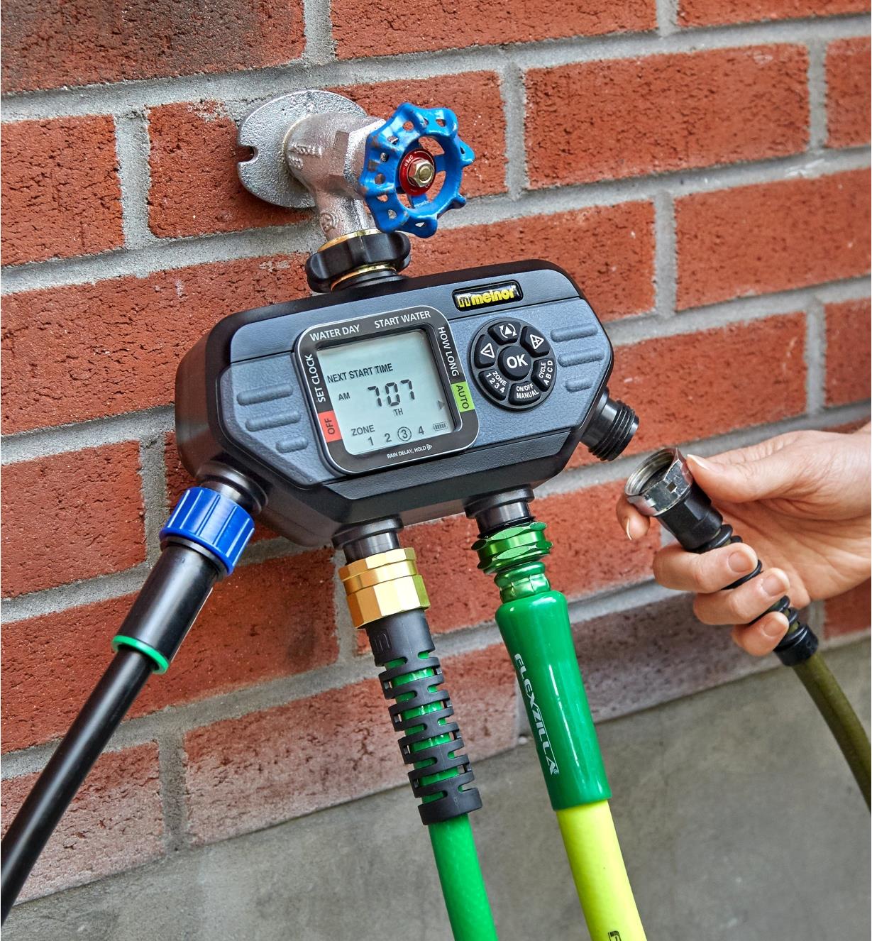 Attaching a hose to one of the electronic water timer’s four outlets