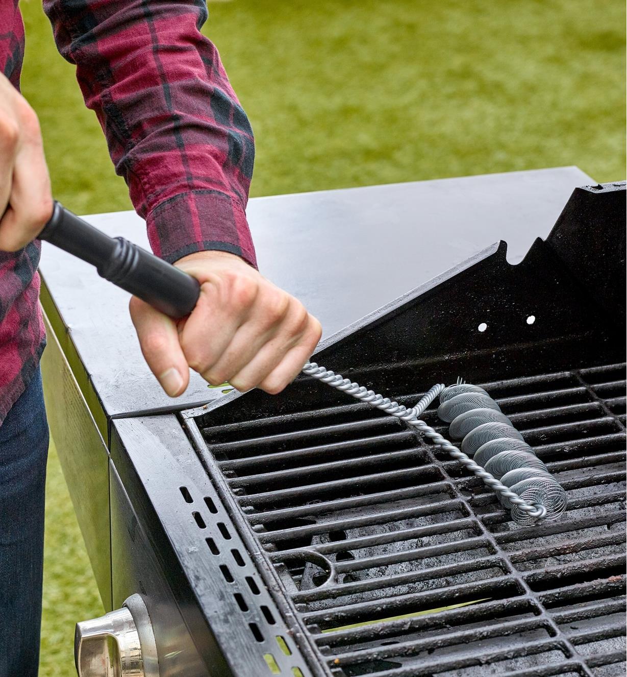 A man cleaning a grill with a bristle-free barbecue brush
