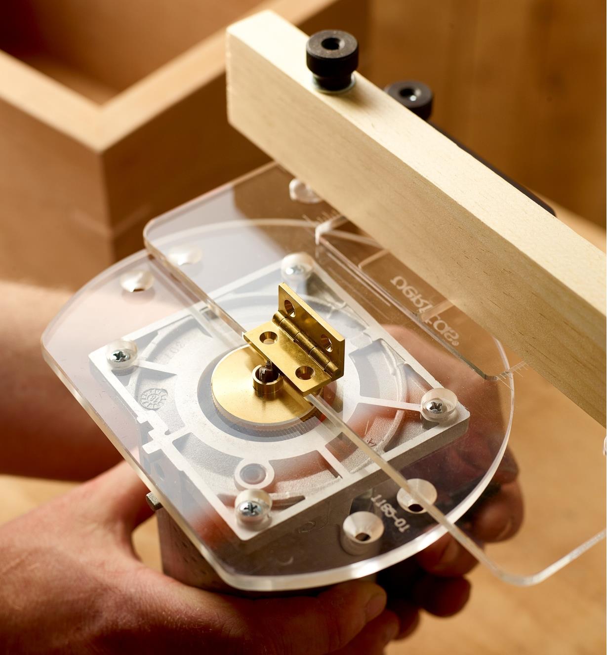 A woodworker sets the cut depth of a router to match the thickness of a cabinet hinge