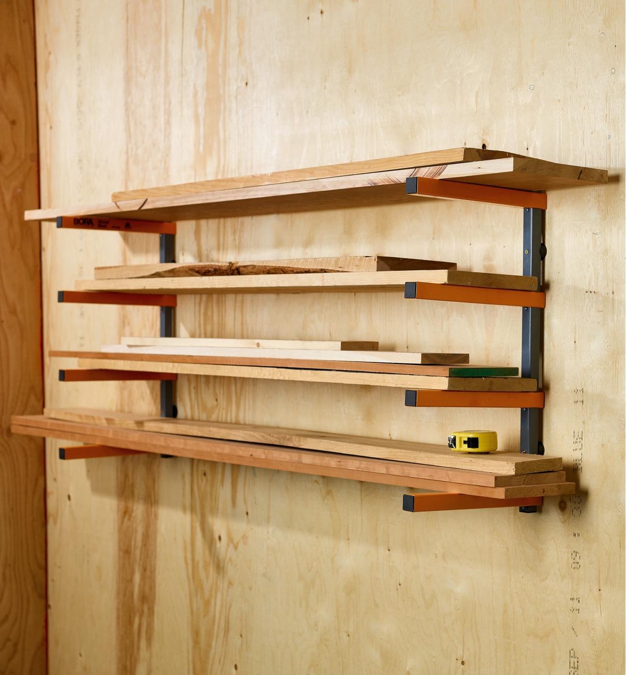 A measuring tape sits on wooden boards stacked on a Bora four-shelf lumber rack