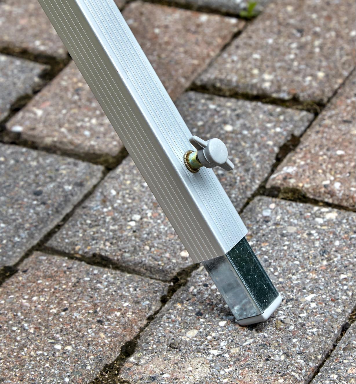 Gros plan du pied réglable stabilisant la table pliante en aluminium sur les sols inégaux