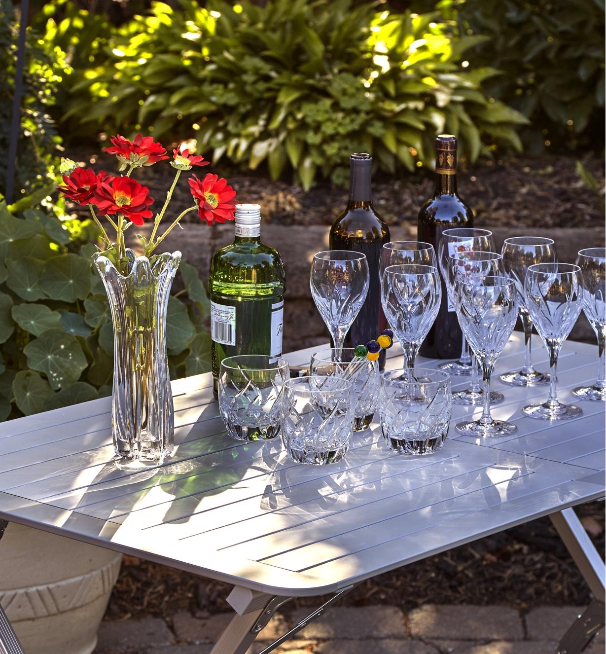 Bouteilles de vin, verres et vase de fleurs sur une table pliante en aluminium