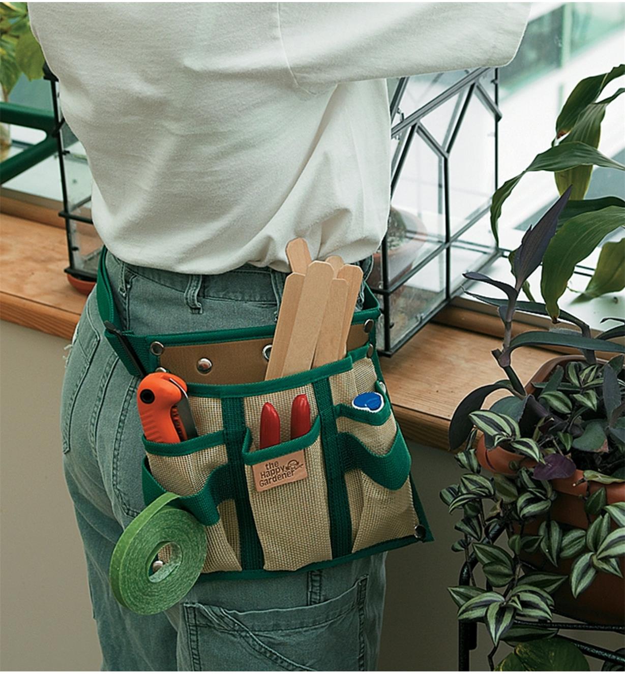 A woman wearing a 4-Pocket Tool Pouch and Belt in a greenhouse