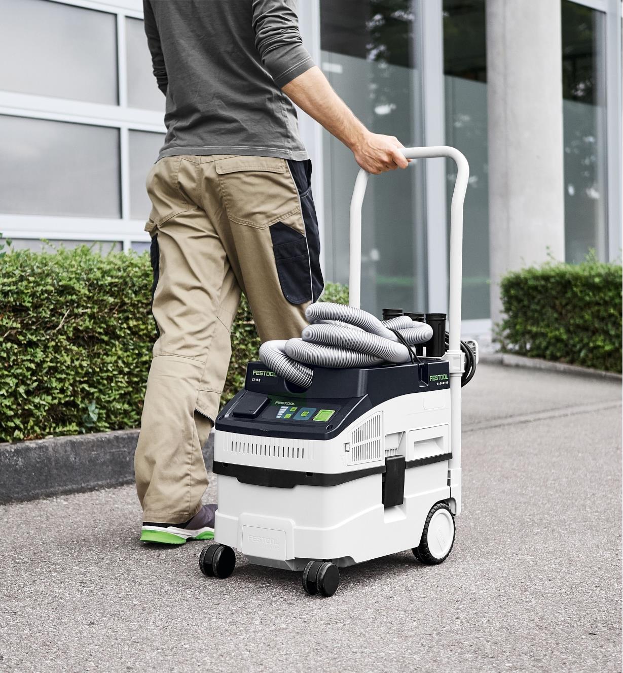 A person pulling a Festool dust extractor using the handle