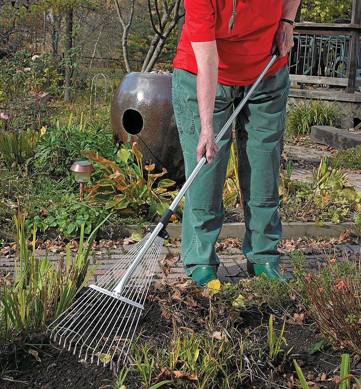 A woman rakes between garden plants using a Long-Handled Rake